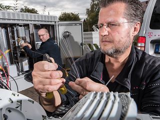 A technician cuts individual optical fibers using pliers.