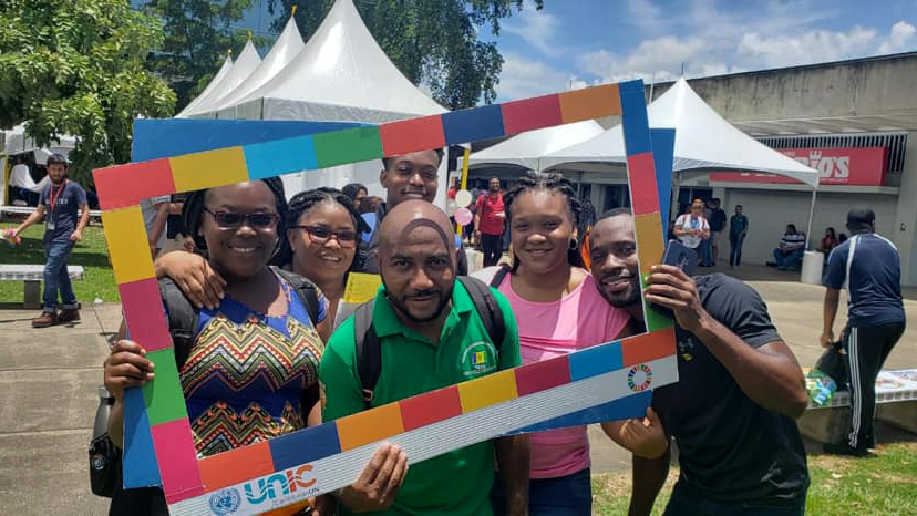 A group of people pose holding up a frame with the SDG colours