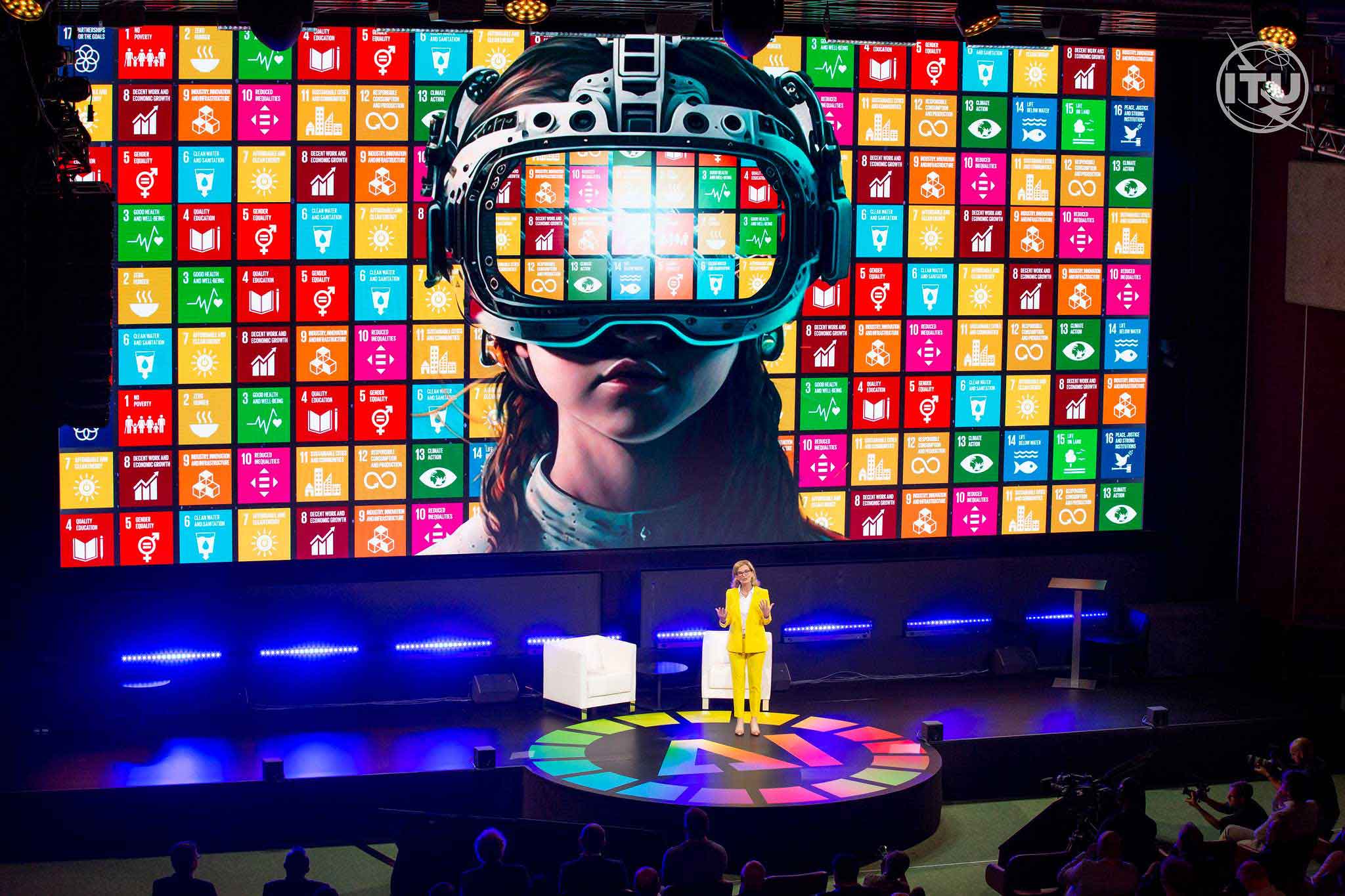 Doreen speaks at the AI for good summit with the SDG logos behind her and an image of a girl wearing an immersive experience headset