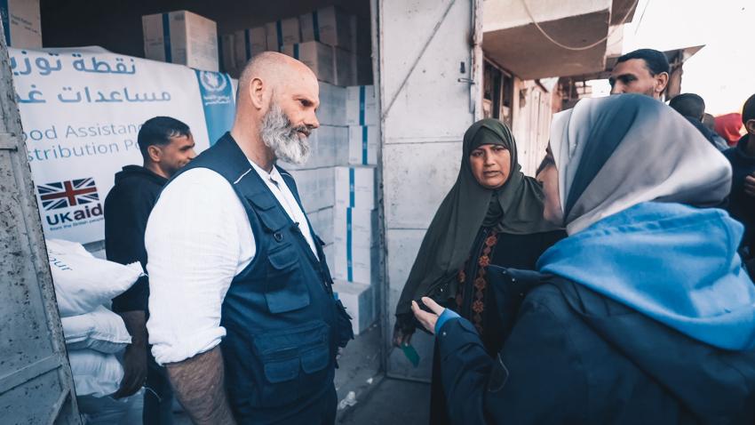 Matthew Hollingworth talking to two women in headscarves in front of warehouse.