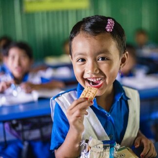 A smiling schoolgirl having WFP’s fortified biscuit. Photo credit: WFP/Sayed Asif Mahmud