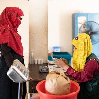 A Rohingya woman receiving her purchased goods at the e-voucher outlet in the Rohingya camps. Photo credit: WFP/Nihab Rahman