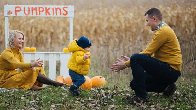 toddler playing in pumpkin patch